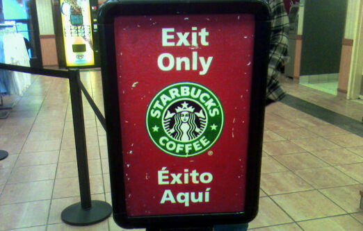 cartel de una cafetería Starbucks que traduce "exit here" como "éxito aquí", cuando el false friend "exit" significa "salida"