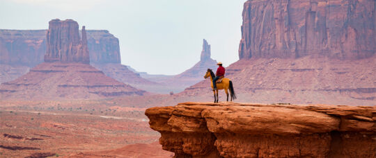 Un vaquero a caballo contempla desde un barranco contempla el paisaje desde un barranco.