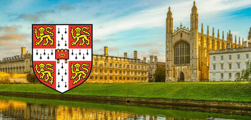 una fotografía del hermoso edificio gótico de la Universidad de Cambridge, con el escudo en primer plano, que tiene leones dorados sobre fondo blanco y rojo