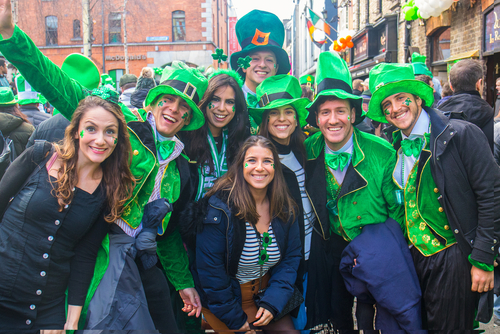 grupo de gente festejando San Patricio en la calle, vestidos con trajes y sombreros verdes