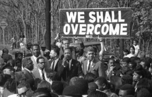martin luther king con pancarta que dice we shall overcome