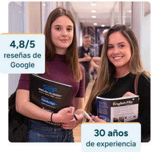 Dos estudiantes en las instalaciones modernas de la academia en Gran Vía 50 mirando a cámara; destacan 30 años de experiencia enseñando inglés y una valoración de 4,8 sobre 5 en Google Reviews