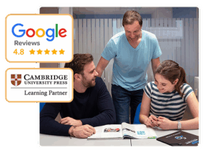 Profesor sonriente enseñando a dos alumnos adultos que estudian inglés juntos en un aula moderna. En la imagen se destacan las valoraciones de Google con 4.8 estrellas y el sello de socio de Cambridge University Press, porque nuestra academia es centro preparador oficial.